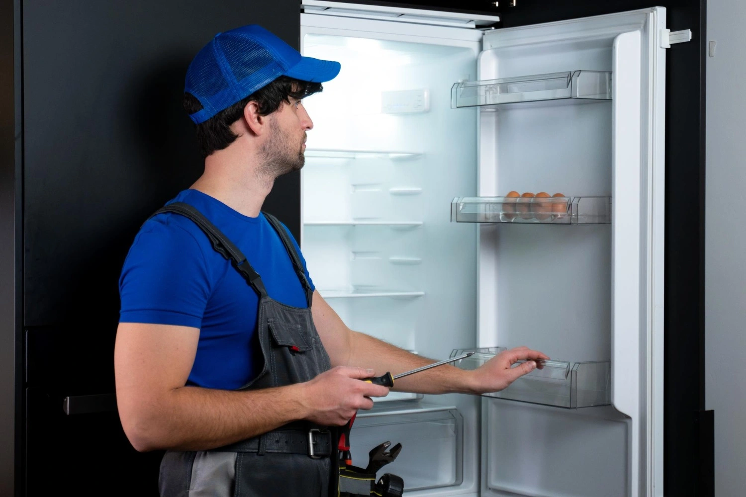 Technician cleaning Sub-Zero refrigerator coils in a Beverly Hills kitchen